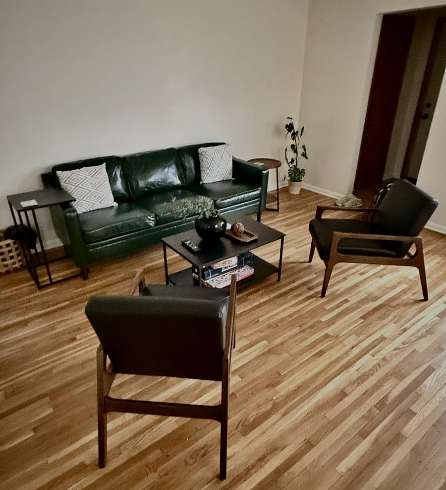 The living room featuring beautiful original hardwood floors and abundant natural lighting! Enjoy the newly added furniture pieces that are comfy and easy to clean.