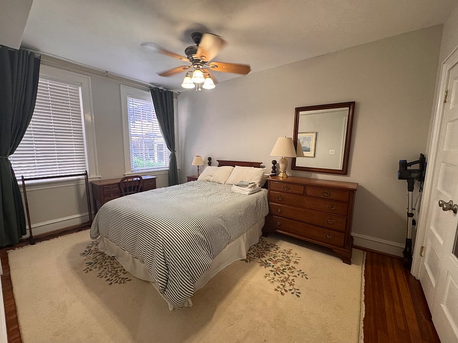 Bedroom with queen sized bed, large closet, dresser & desk, vacuum. Blinds and floor to ceiling blackout curtains for windows