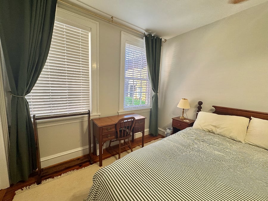bedroom with desk, blackout curtains and blinds.