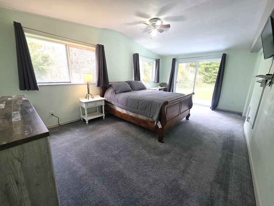 Spacious primary bedroom with comfortable bed and natural light