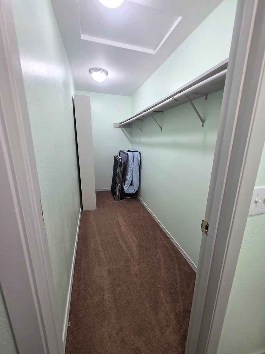 Bunk room walk in closet with shelving and additional rollaway bed for extra guests