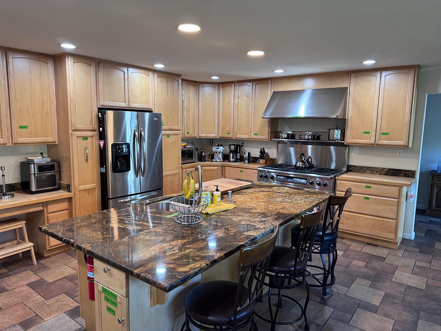 Spacious kitchen with ample wood cabinetry, stainless-steel appliances, and a large island with bar seating for meals.