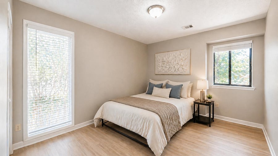 Well-sized bedroom with two large windows, neutral finishes, and space for a full/queen bed plus a nightstand.