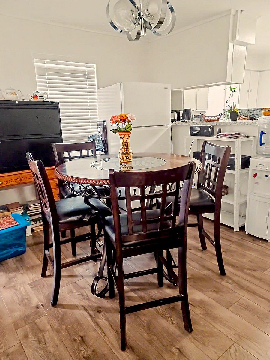 Dining area with a round glass-top table, seating for four, and easy access to the adjoining kitchen and appliances.