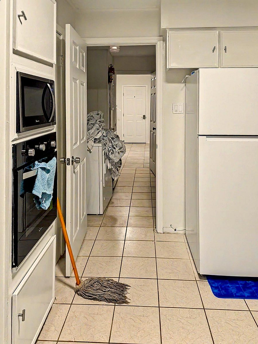 Galley-style kitchen with ample cabinet storage, full-size refrigerator, and built-in oven for convenient meal prep.