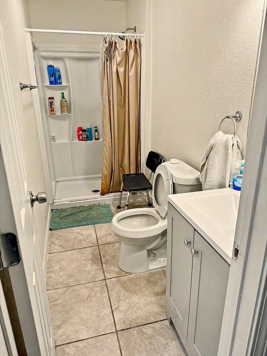 Full bathroom with a tub/shower combo, built-in shower shelving, and a vanity with storage over tile flooring.