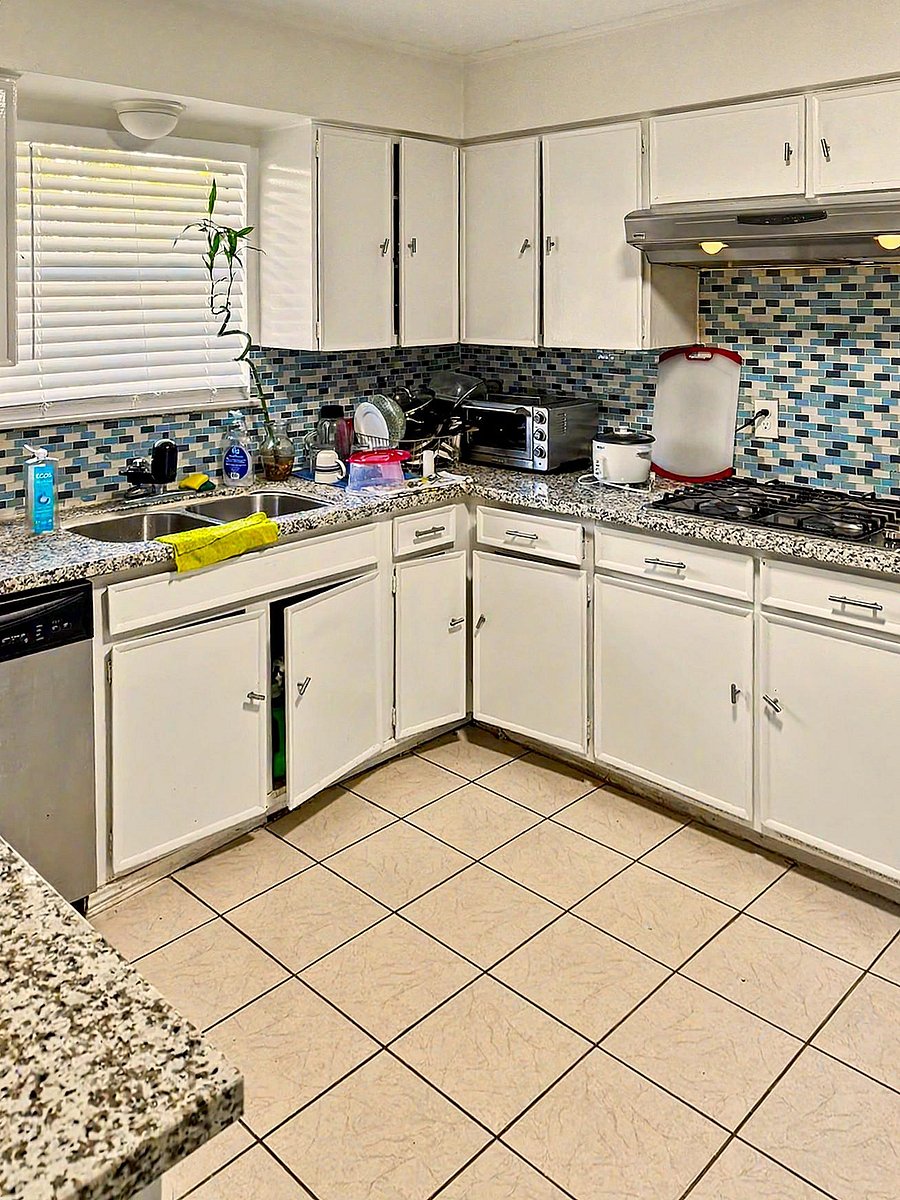 U-shaped kitchen with ample cabinet storage, granite-look counters, mosaic tile backsplash, and a gas range under vent hood.