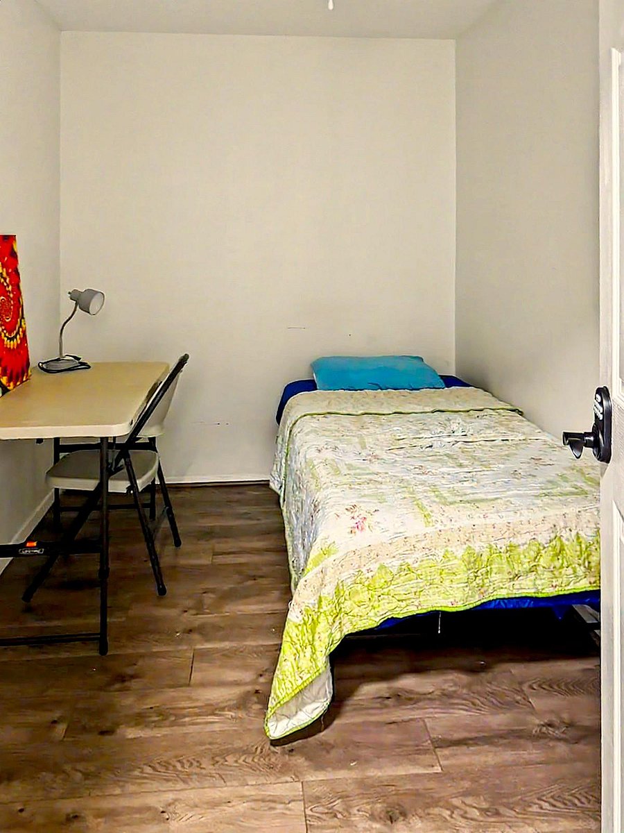 Private furnished bedroom with a twin bed, work desk, and durable wood-look flooring--ideal for studying and relaxing.