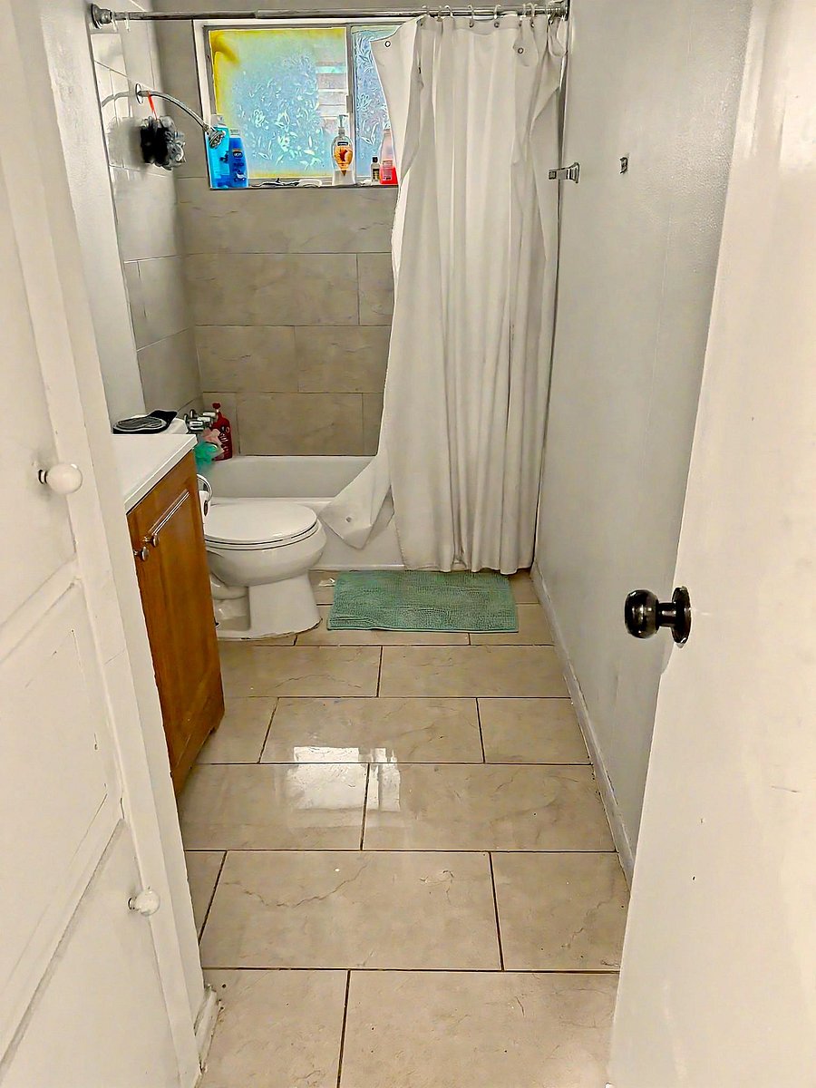 Full bathroom with a tub/shower combo, tiled surround, and a window for natural light and ventilation.