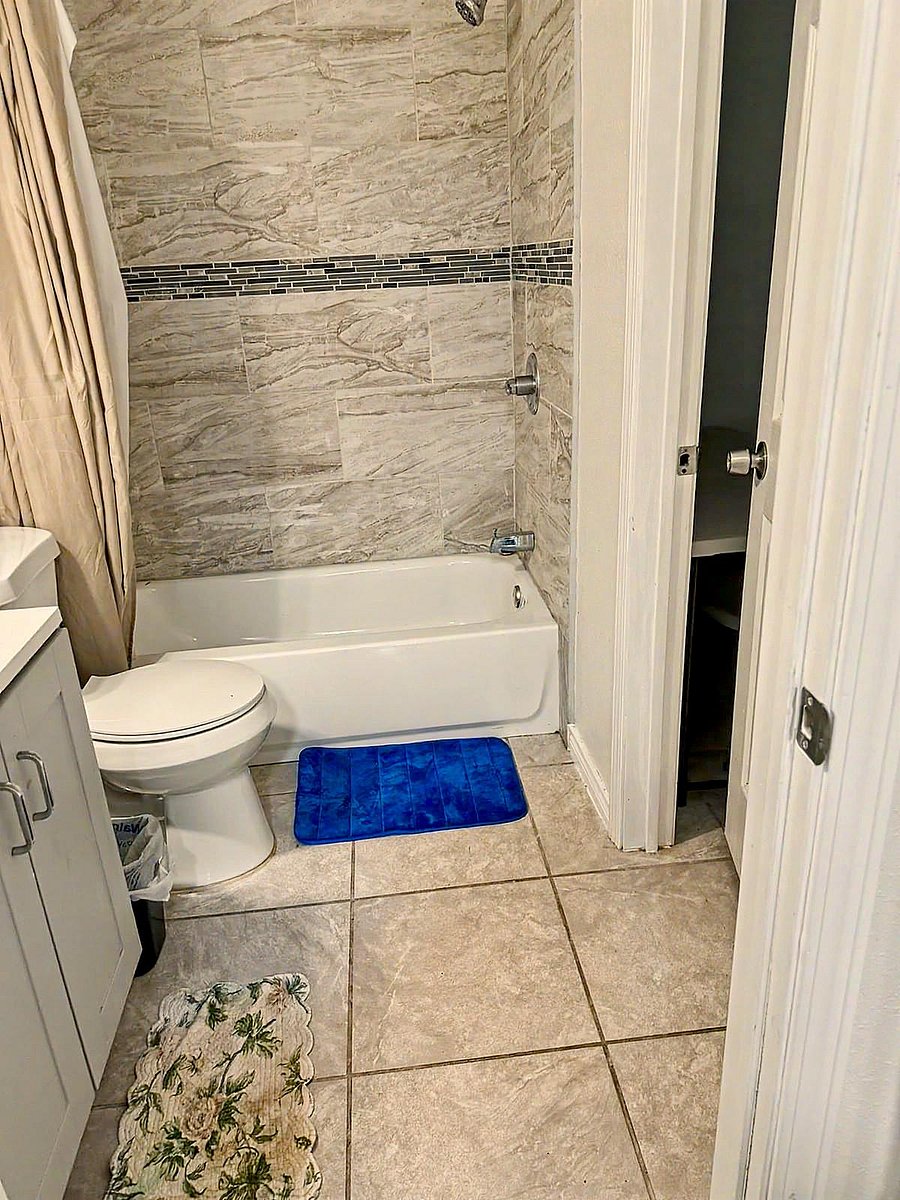 Full bath with tub/shower surround in tiled finishes, plus a vanity cabinet and durable tile flooring for easy upkeep.