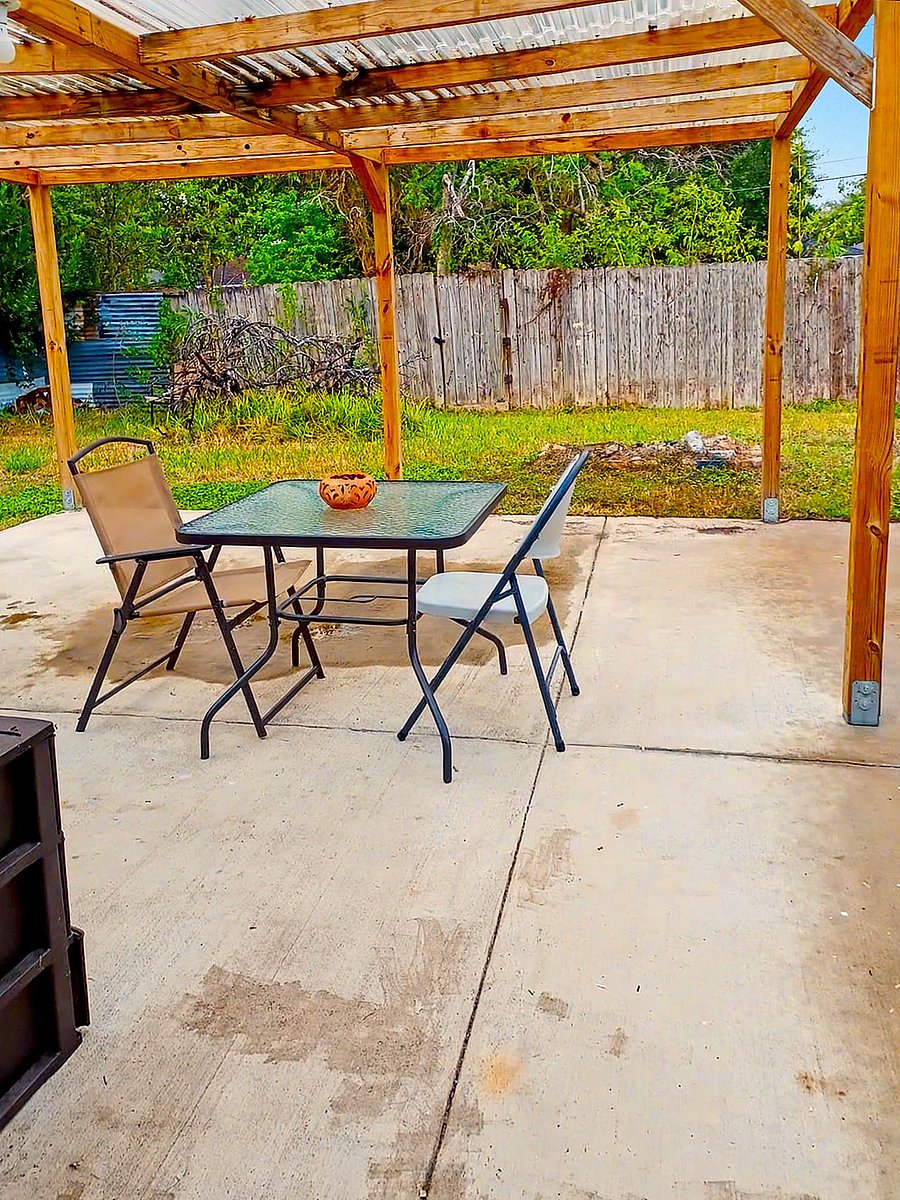 Covered backyard patio with a pergola roof and concrete pad, offering space for outdoor dining and relaxing.