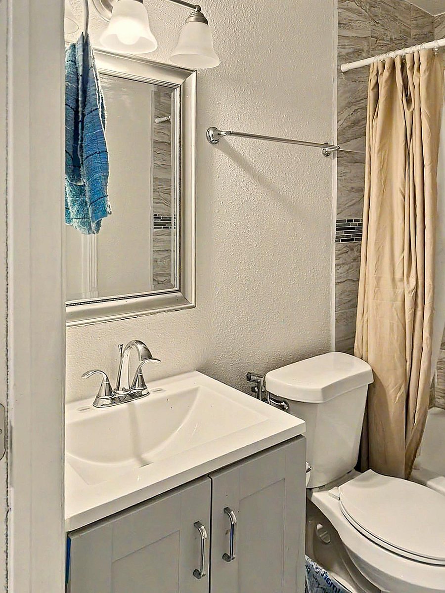 Updated full bathroom featuring a single-sink vanity with storage, framed mirror, and tiled tub/shower surround.
