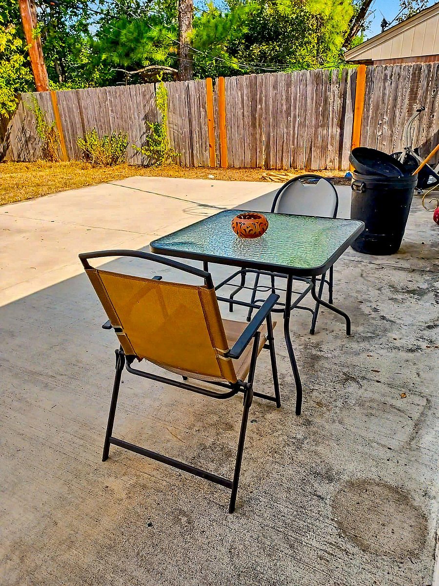 Concrete patio with a small outdoor table set, offering a fenced backyard area for relaxing or dining outside.