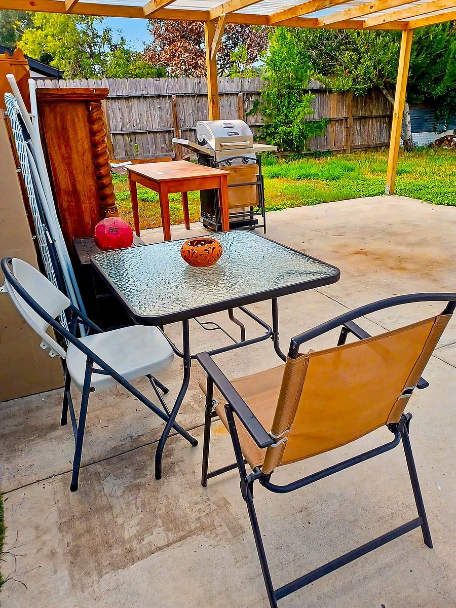 Covered backyard patio with a concrete slab, outdoor dining set, and grill, plus a fenced yard for relaxing outdoors.