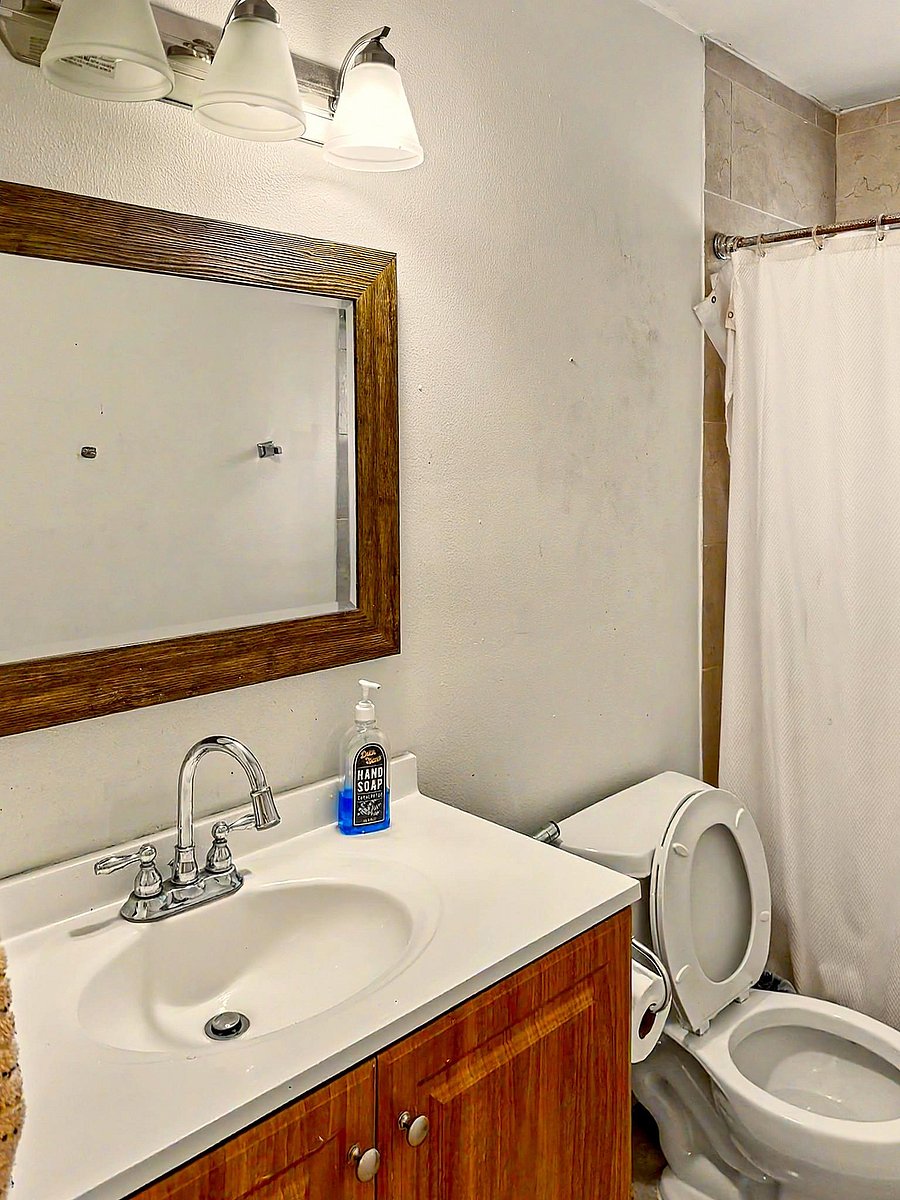 Bathroom with a single-sink vanity, framed mirror, and tub/shower combo with tile surround and curtain rod.