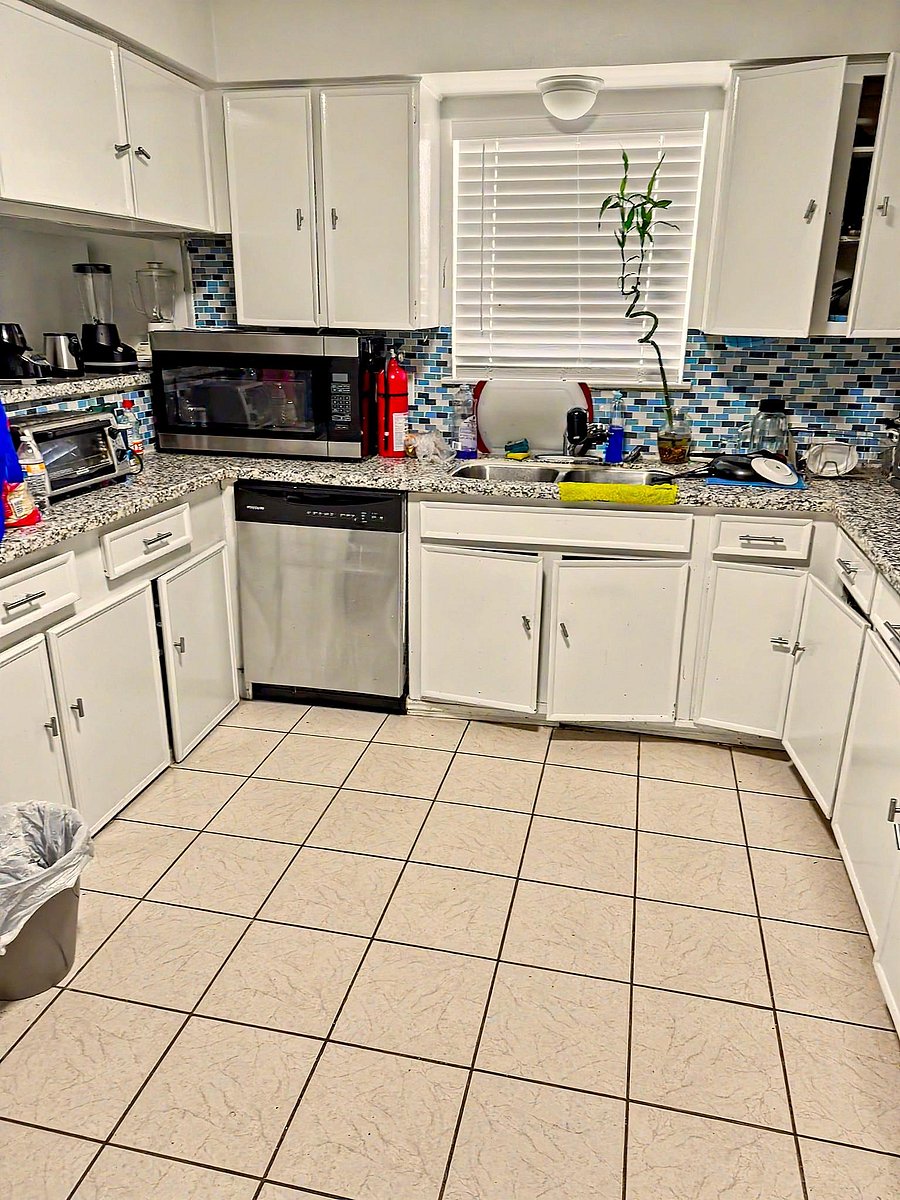 Efficient U-shaped kitchen with ample cabinetry, tiled backsplash, and generous counter space with dishwasher and sink.