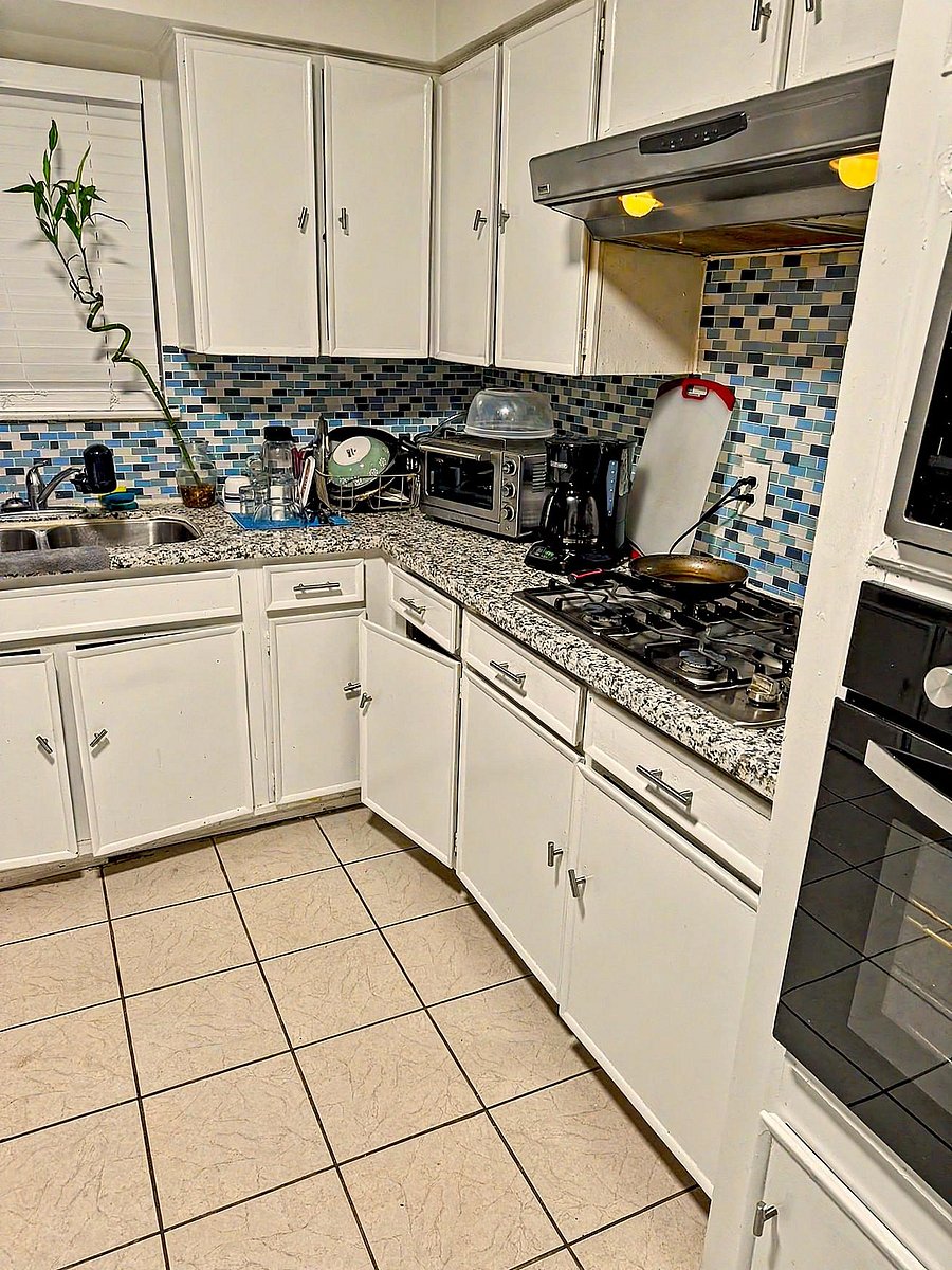 Efficient L-shaped kitchen with ample cabinetry, gas cooktop, and generous granite-look counters for meal prep.