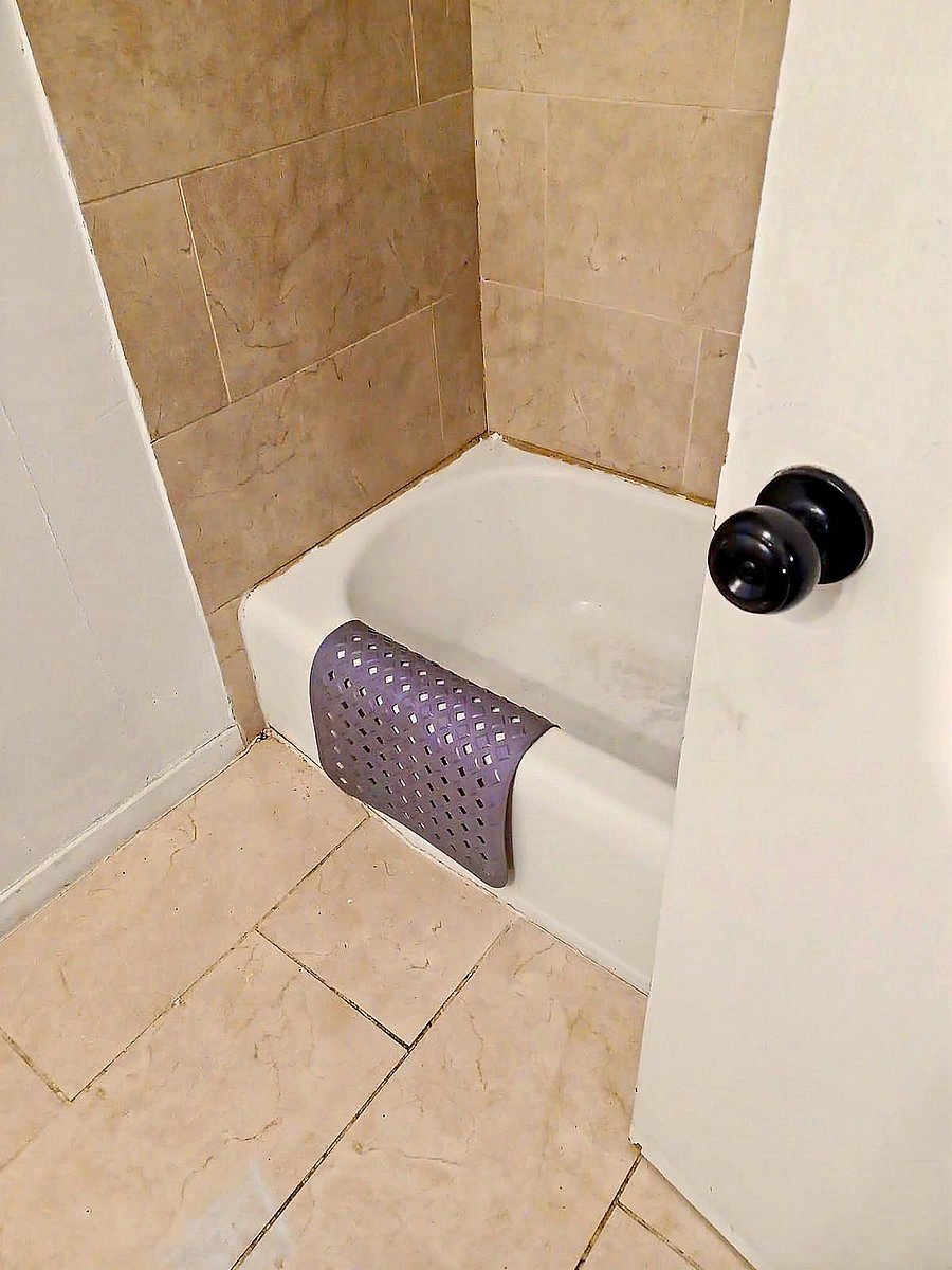 Tiled tub/shower surround with a standard bathtub and durable tile flooring for easy cleanup and daily use.
