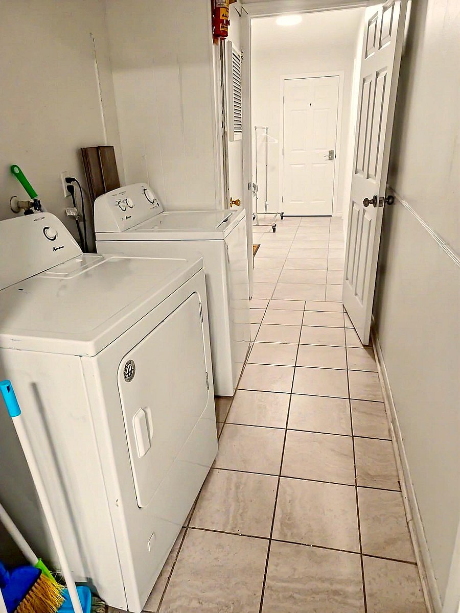 Dedicated laundry area with full-size washer and dryer, tile flooring, and convenient access from the hallway.