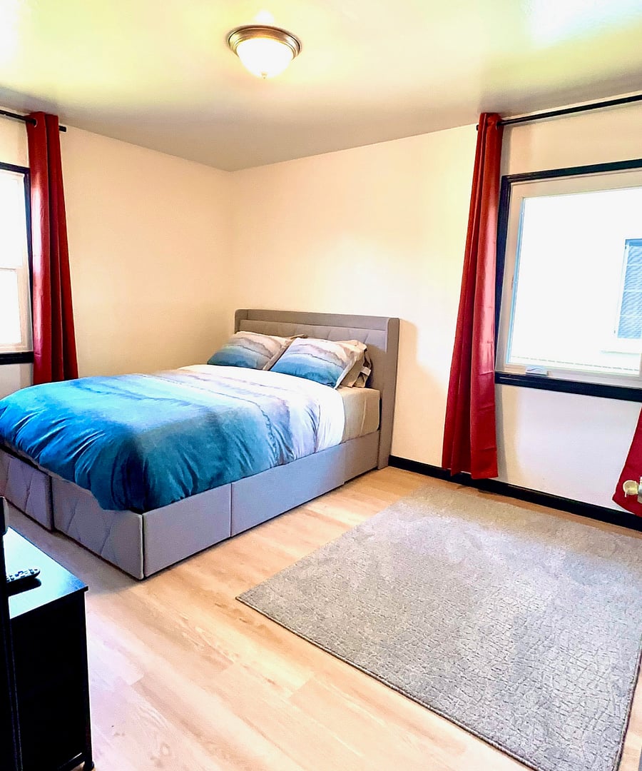 Cozy private bedroom #2 with a comfortable queen-size bed and a 55 smart TV for your favorite streaming. Blackout curtains create a cozy, private space. Enjoy natural light and relaxing backyard views, perfect for unwinding after a long day.