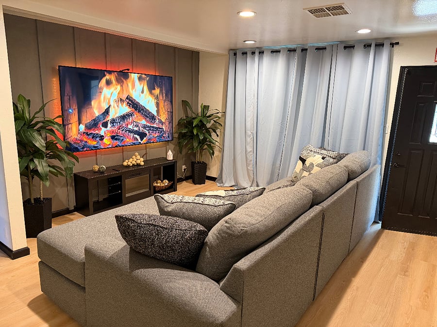 Relax in a stylish living room featuring a plush oversized couch perfect for lounging. Blackout curtains create a cozy, private atmosphere, ideal for movie nights or unwinding anytime of day.