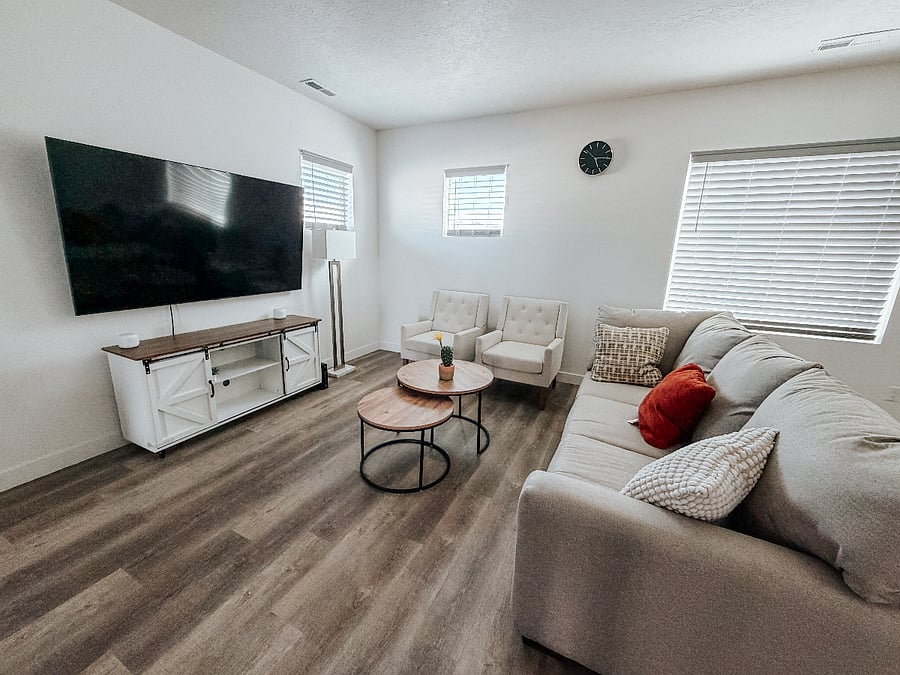 Bright & Spacious Living Room

Cozy living area featuring a large wall-mounted Smart TV, comfortable sectional sofa with accent pillows, two matching armchairs, and stylish nested coffee tables. Plenty of natural light and modern finishes throughout.