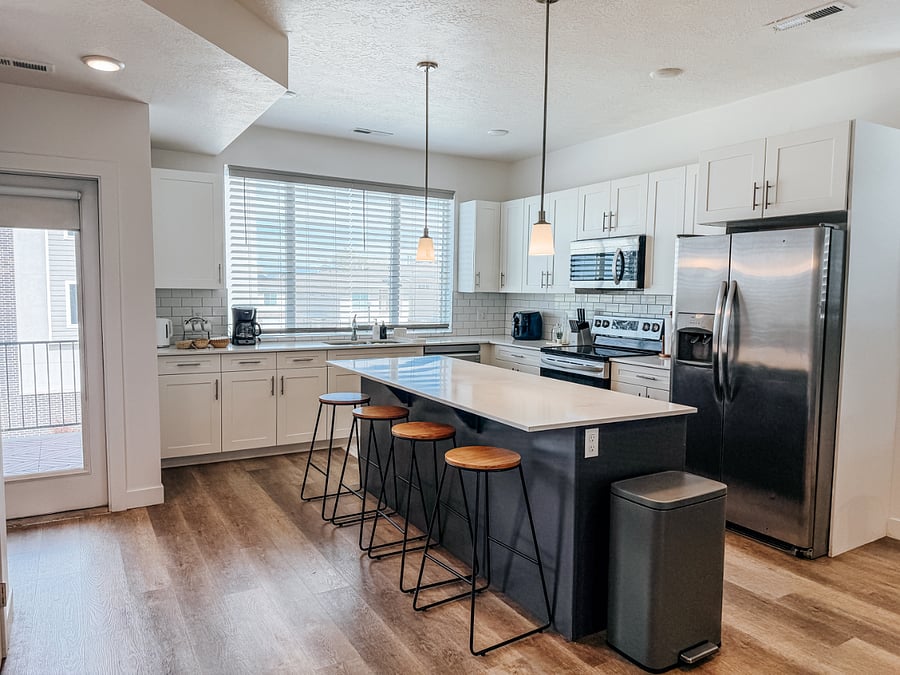 Bright kitchen featuring a spacious center island with barstool seating for 4, stainless steel appliances, and direct access to the private balcony.
