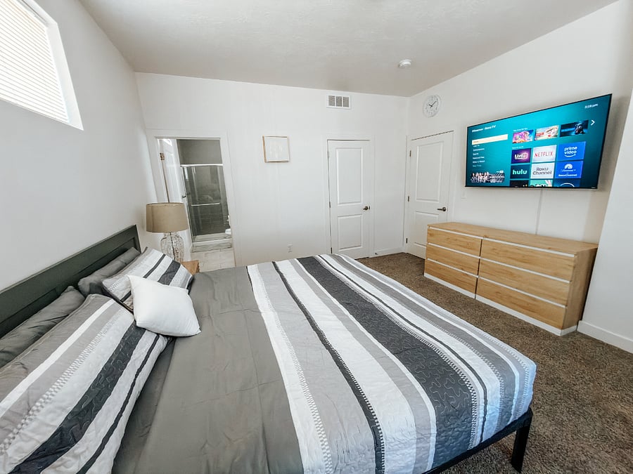 Primary Master Bedroom with Full Bathroom

Spacious 2nd-floor master bedroom featuring a comfortable king bed with green bedding, large window with blackout curtains for better sleep, wall-mounted TV, and direct access to a private full bathroom.