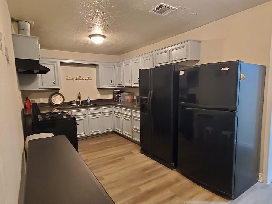 Spacious kitchen with two full-size refrigerators and a large table -- plenty of room for shared meals.