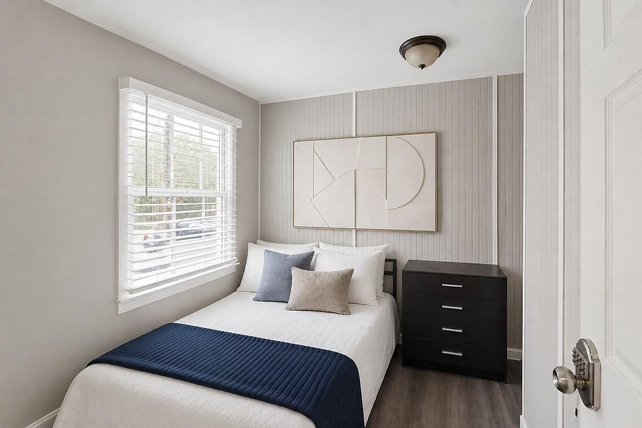 Well-appointed bedroom with a large window and blinds, space for a full bed, and a dresser for convenient storage.