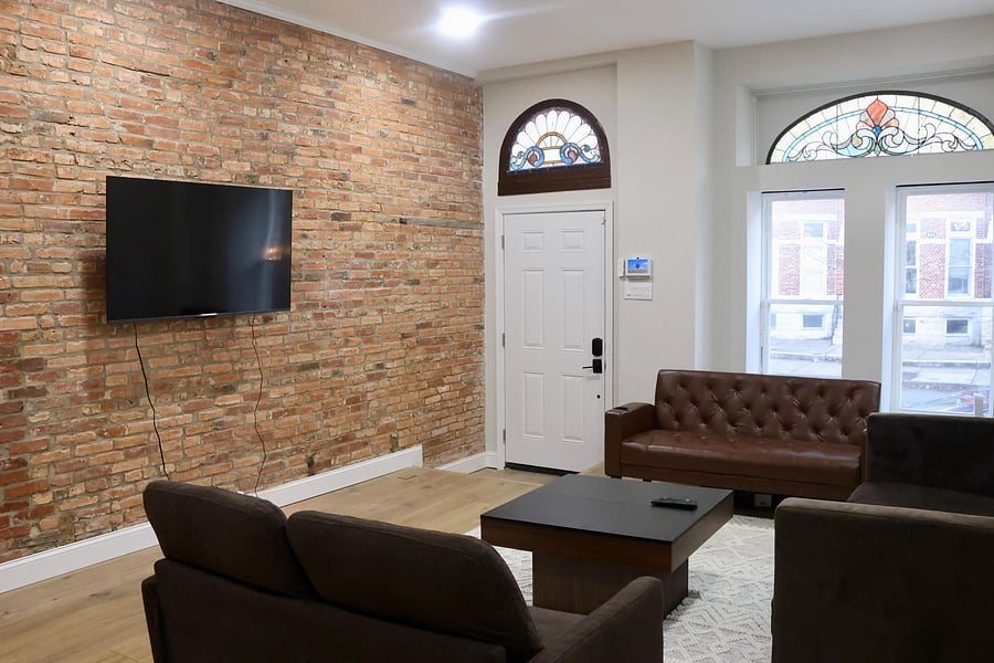 Living room; showcasing the exposed brick and preserved historic Baltimore stained glass transom windows