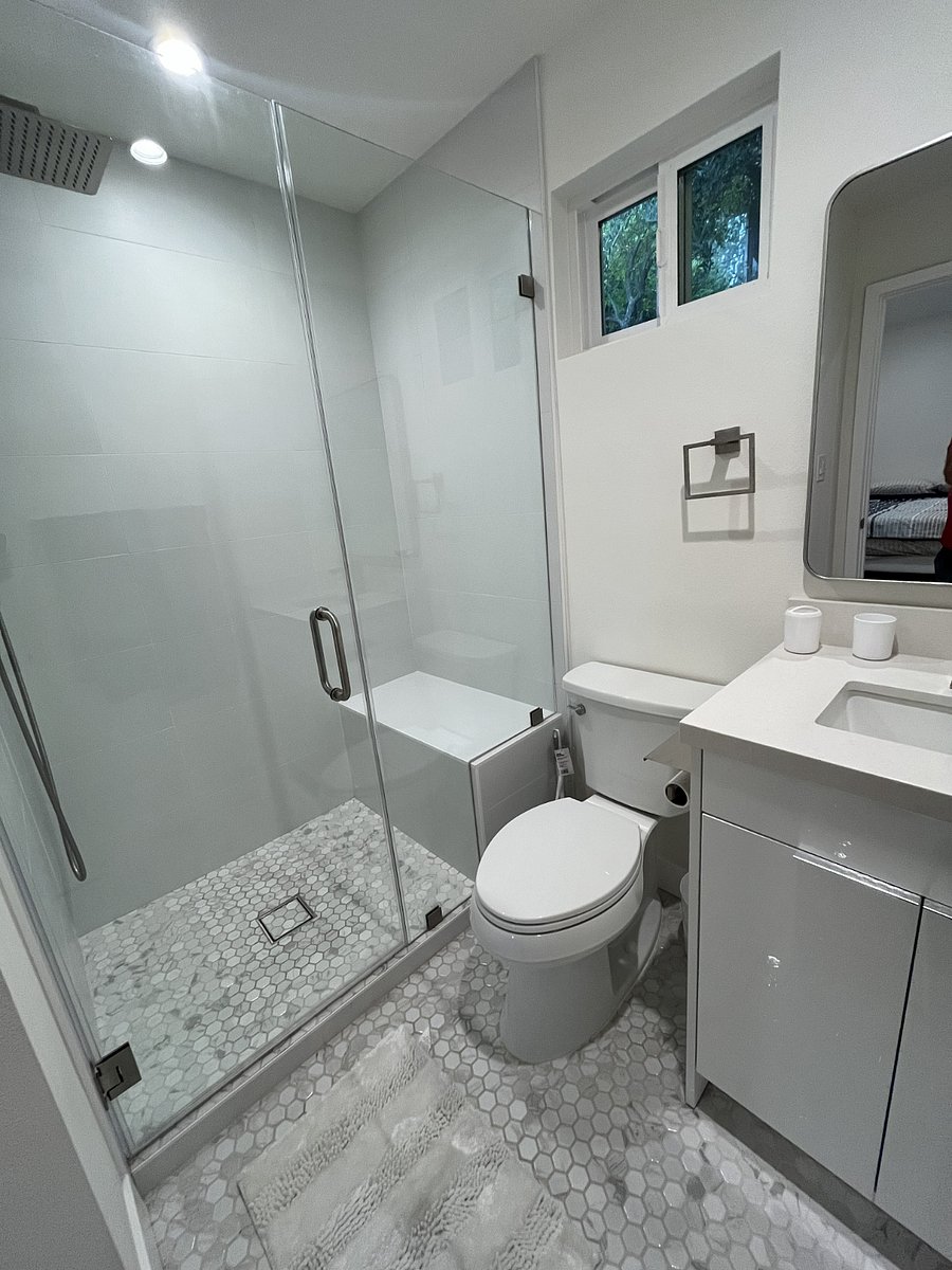Audreys bathroom features a tiled walk-in shower with rain shower head and handheld sprayer, toilet, sink with Caesarstone countertop and storage. A whisper quiet fan works efficiently in the modern space.