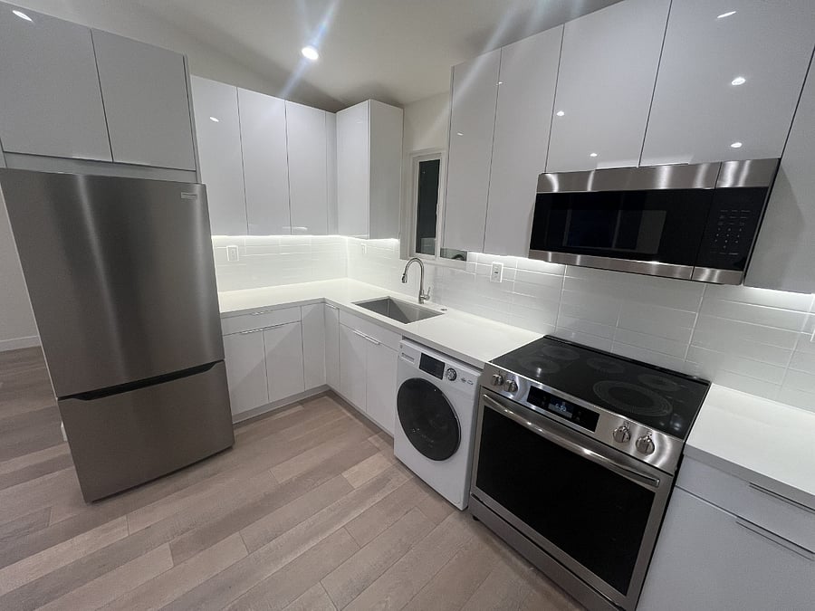 The kitchen features stainless steel Frigidaire Gallery Bottom Freezer Refrigerator, Front Control Electric Total Convection Range, an Over the Range Microwave, and a GE Undercounter Washer Dryer Combo.