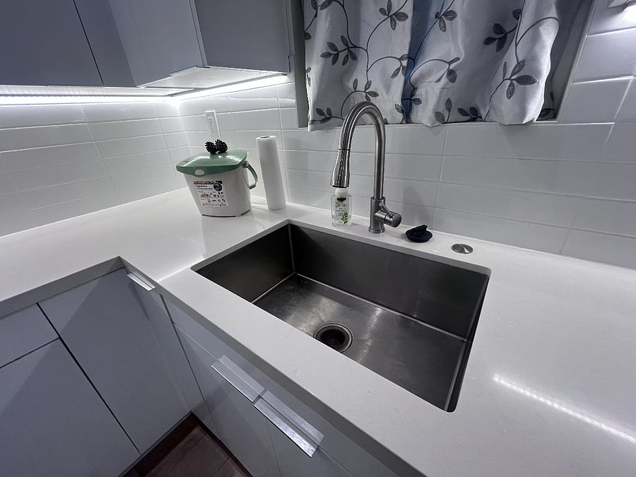 The kitchen features a deep stainless steel sink with a sprayer incorporated in the faucet.