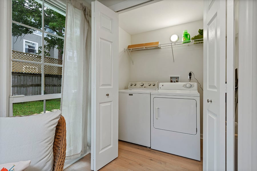 In the sunroom is the new laundry room with a new washer and dryer, and ironing board, iron and drying rack. 