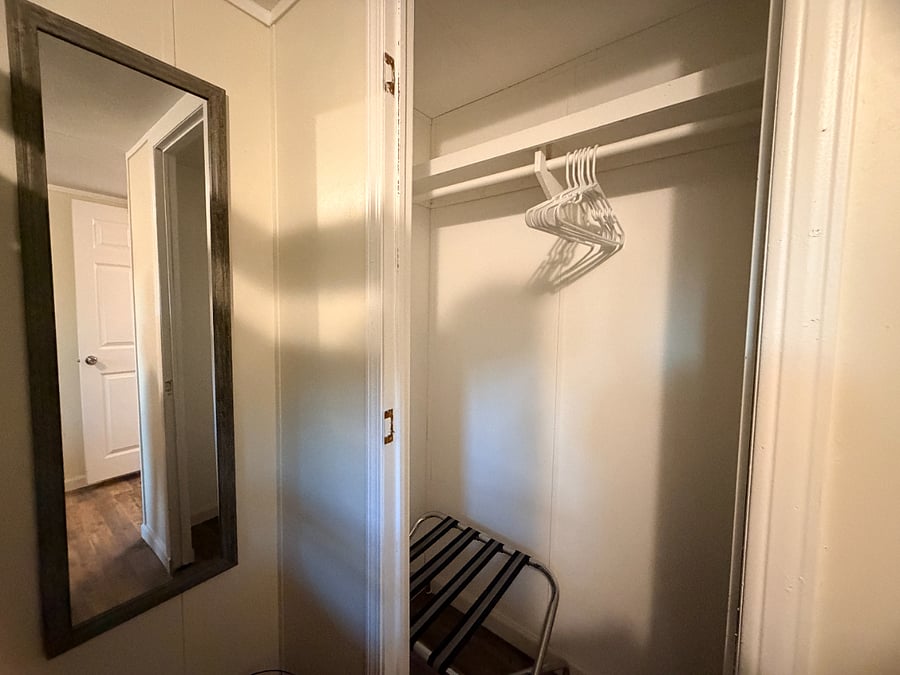 The bunkbed bedroom view of the wall mirror and a closet. The closet has one luggage rack.