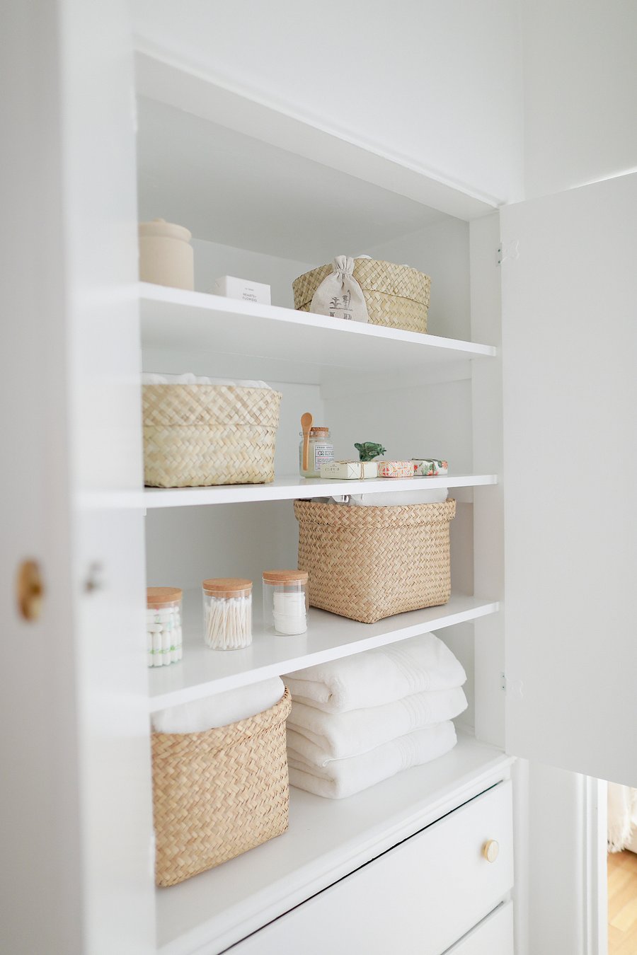Stocked linen closet with towels, toiletries, and woven storage baskets.