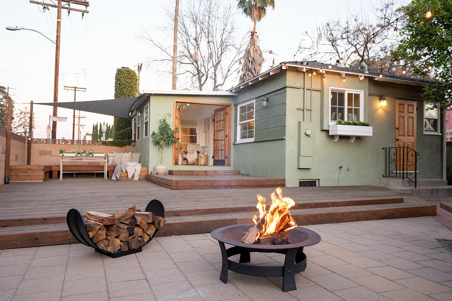 Backyard at golden hour with fire pit, string lights, and lounge seating.