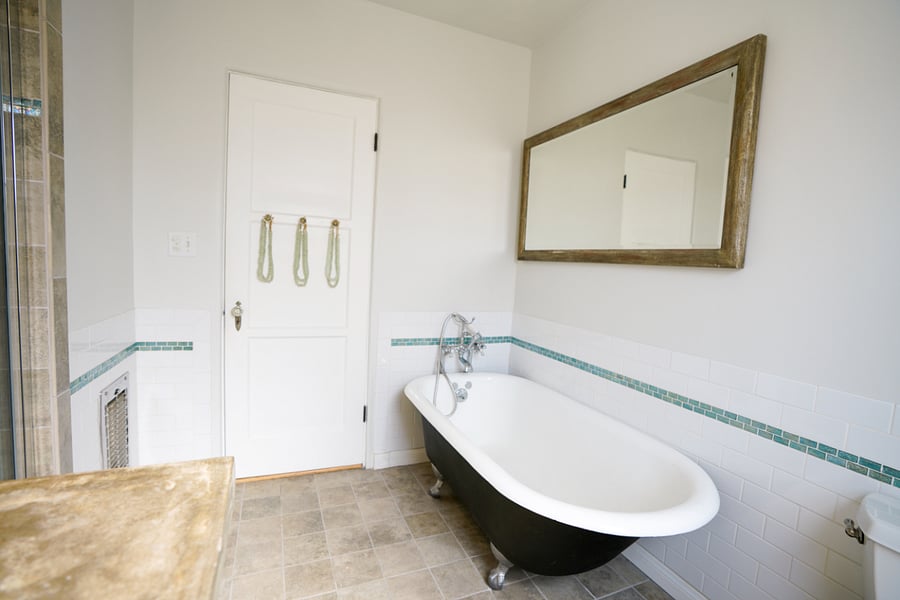 Bathroom with clawfoot soaking tub, classic tilework, and soft natural light.