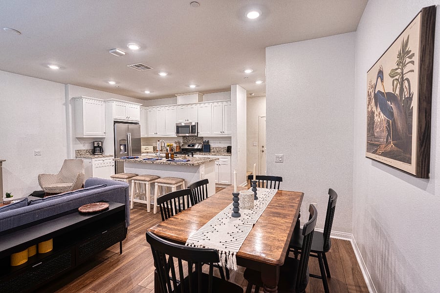 An open-concept dining and kitchen area designed for connection. Enjoy a meal at the spacious wood table or grab a quick bite at the breakfast bar. This versatile layout is ideal for groups wanting to share quality time in a bright, modern setting.