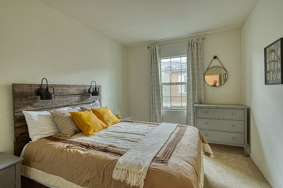 A cozy retreat featuring a rustic wood headboard and warm, inviting tones. This secondary bedroom offers a comfortable queen bed, ample storage, and plenty of natural light, providing a peaceful sanctuary for a restful night's sleep.