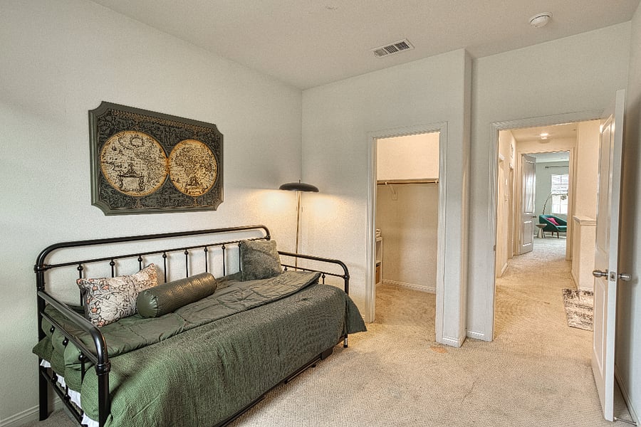 A flexible third bedroom featuring a cozy daybed and a walk-in closet. This bright space serves perfectly as a quiet guest room or a peaceful spot to recharge, maintaining the modern and airy feel found throughout the entire Valencia home.