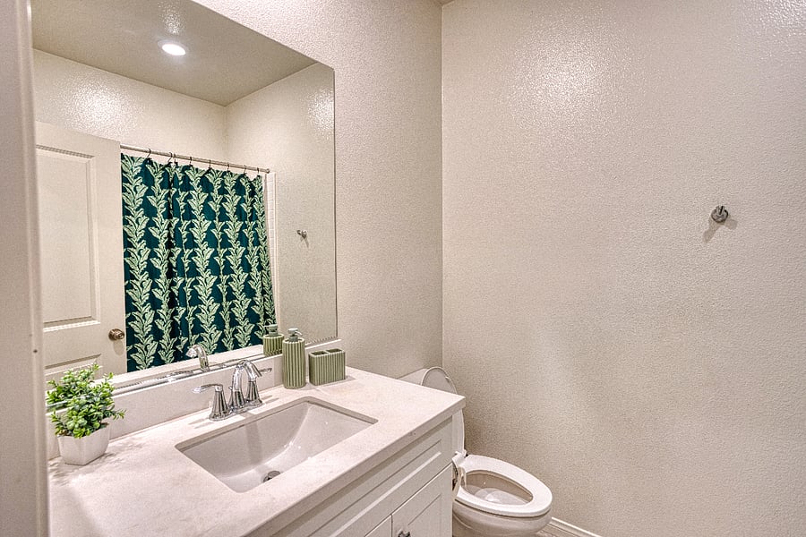 A clean and modern full bathroom located on the upper level. Featuring a spacious vanity, bright lighting, and a bathtub with a stylish shower curtain, it provides a comfortable and refreshed space for guests to use throughout their stay.