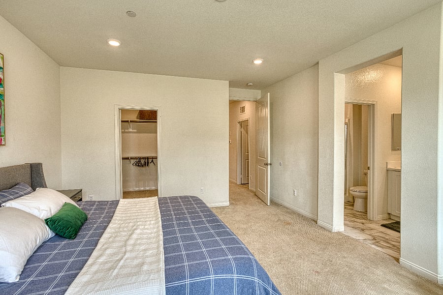 A spacious look at the primary suite, featuring a comfortable king bed, a walk-in closet, and a private en-suite bathroom. This airy retreat provides everything you need for a restful and convenient stay in Santa Clarita.