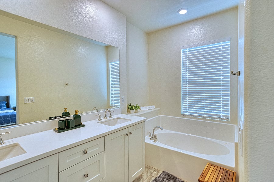 Unwind in the spa-like primary bathroom, featuring a deep soaking tub and a dual-sink vanity. With modern fixtures and a clean, bright atmosphere, its the perfect place to refresh and recharge during your stay.