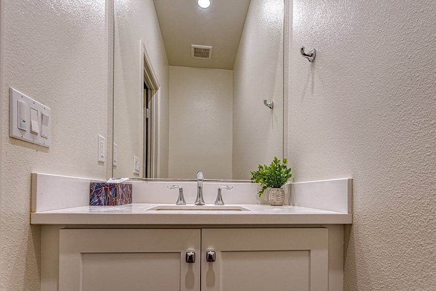The bright, clean first-floor powder room. Features a modern vanity and large mirror, conveniently located near the main living area for easy guest access. Ideal for quick refreshes and daytime convenience.