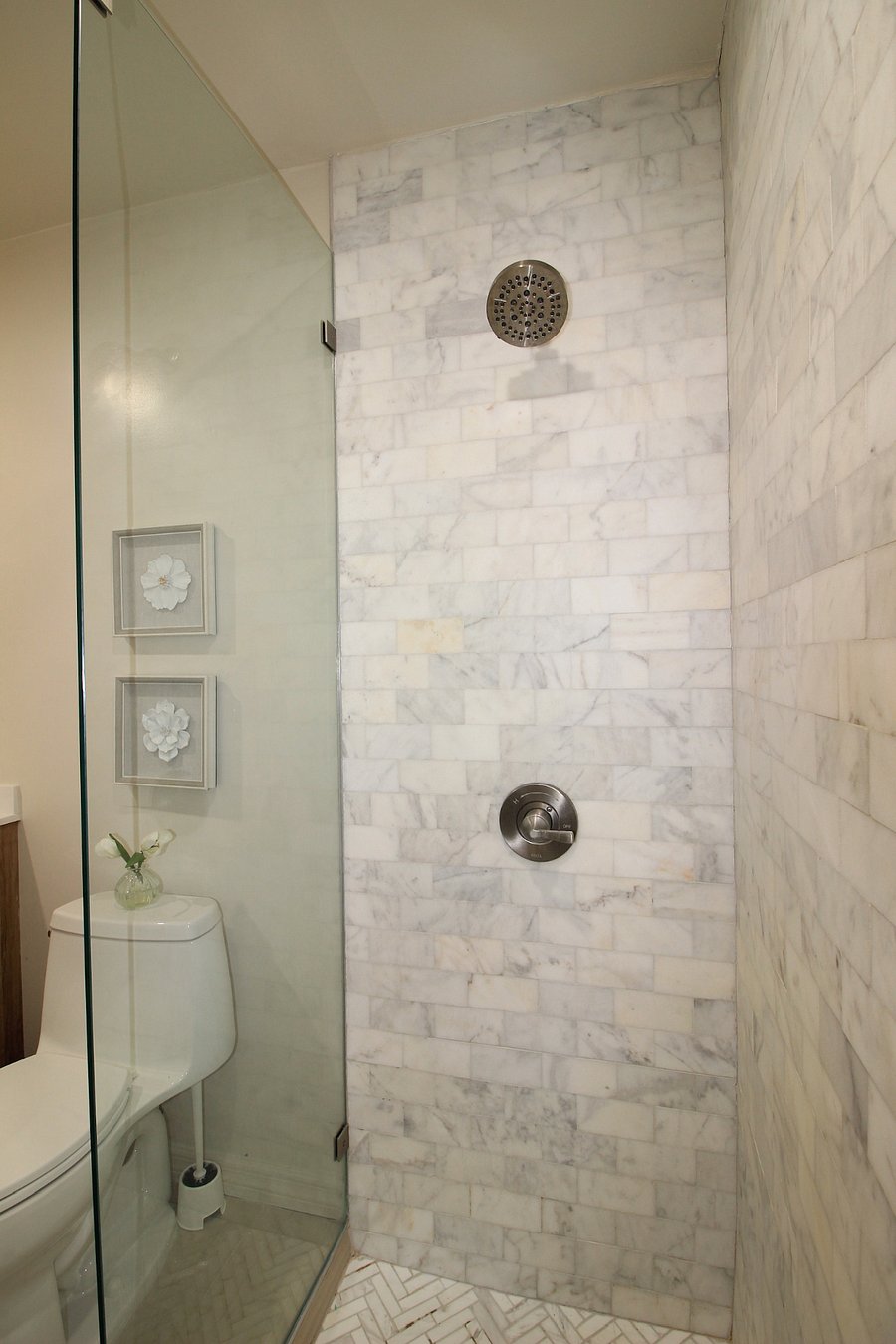 Large marble, walk in shower with marble bench and glass doors. 