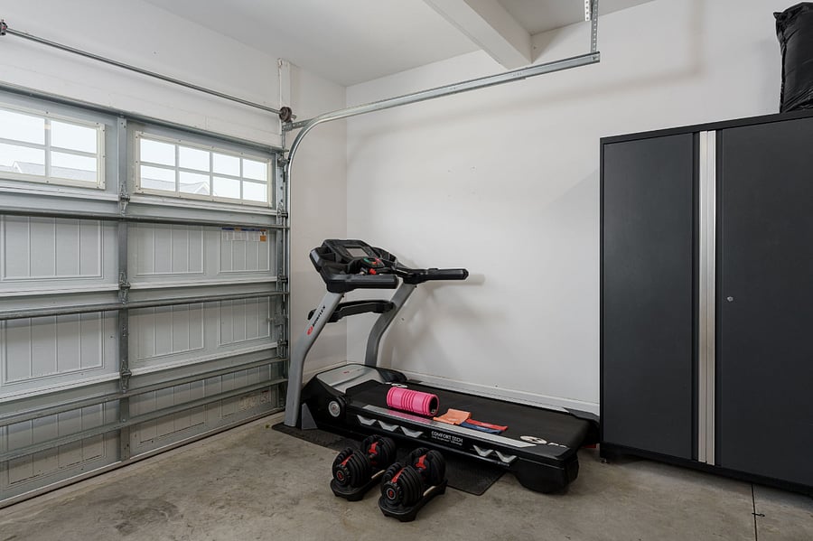 Garage gym with treadmill, weights, and workout bands