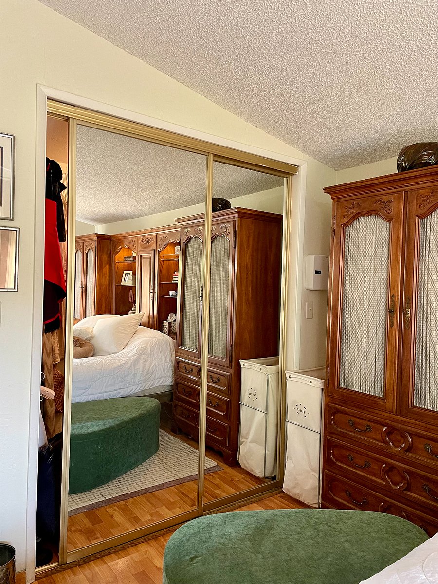 Large walk-in closet features bright overhead lighting, a Tibetan rug, wooden hangers, a shirt rail, trouser rail, medium dress/jacket rail, long dress rail, coat rail, shelving unit for folded items plus top shelves for handbags or extra bedding.
