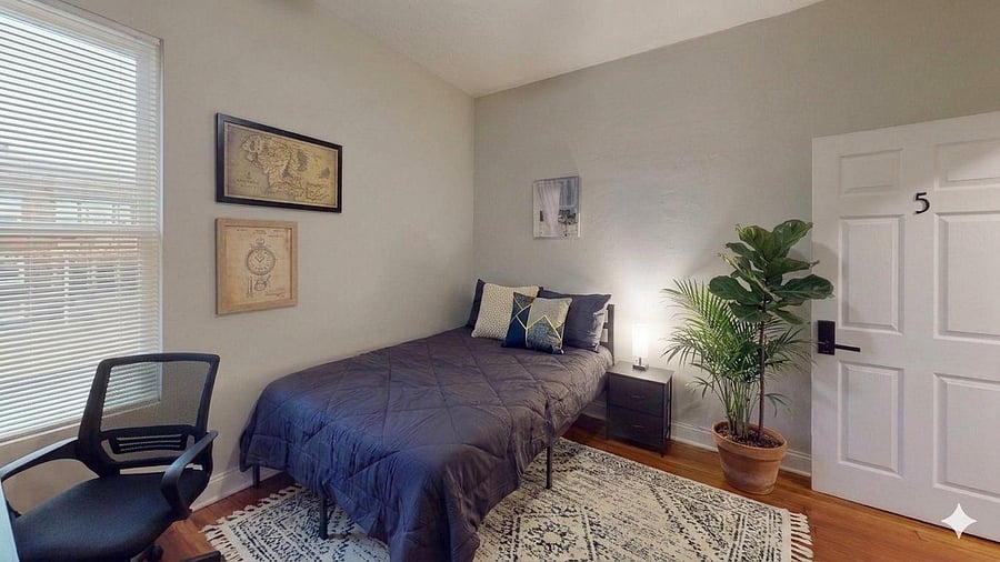 Well-appointed bedroom with a comfortable bed, nightstand, and a window with blinds for natural light and privacy.